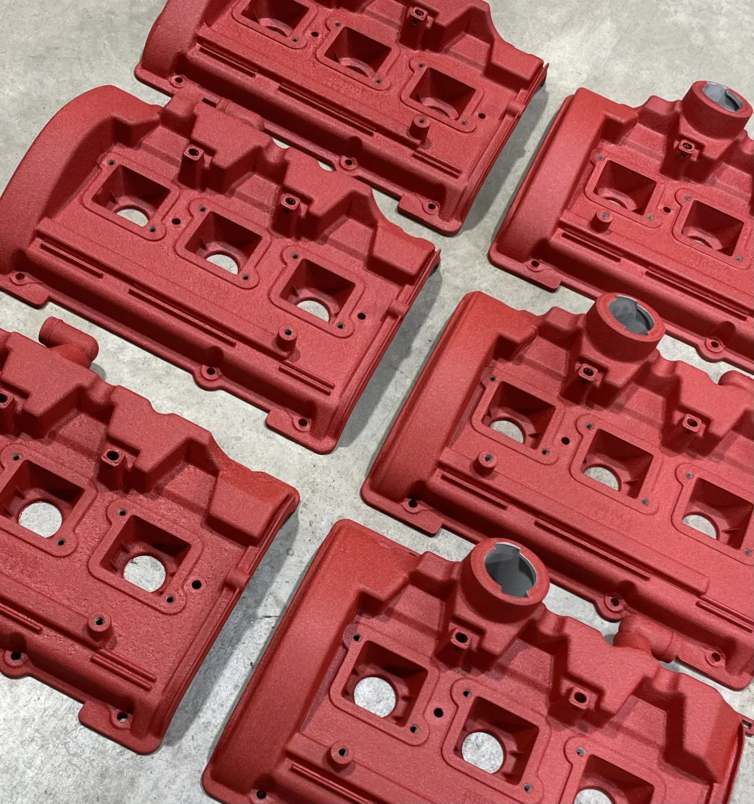 Batch of cam covers finished in textured red, laid out on the shop floor