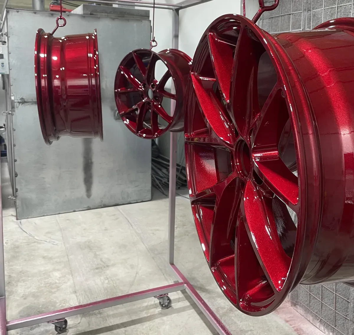 Set of alloy wheels in candy red hanging on the rack after coating