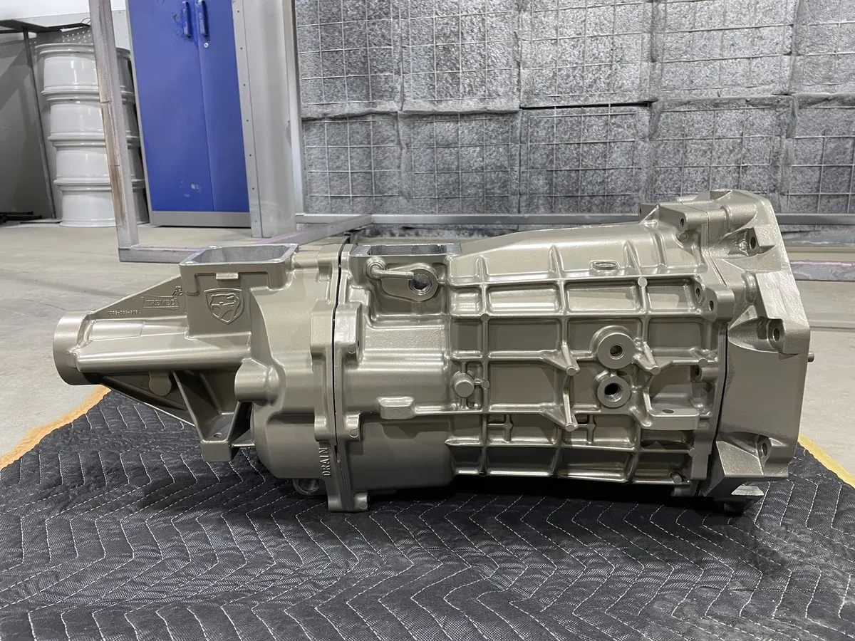 Transmission case finished in champagne metallic, sitting in front of the coating booth