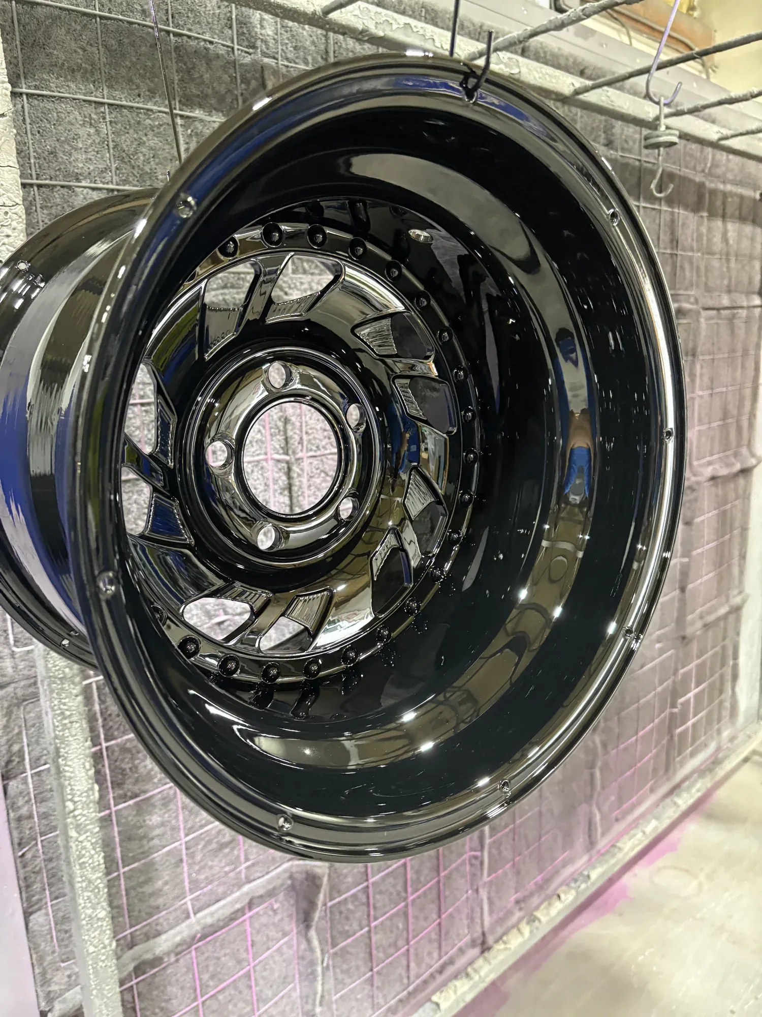 Truck wheel finished in gloss black hanging in the coating booth