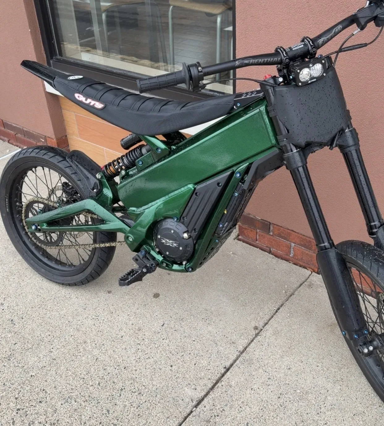 Electric bike built up on a metallic green powder coated frame, standing against a brick wall
