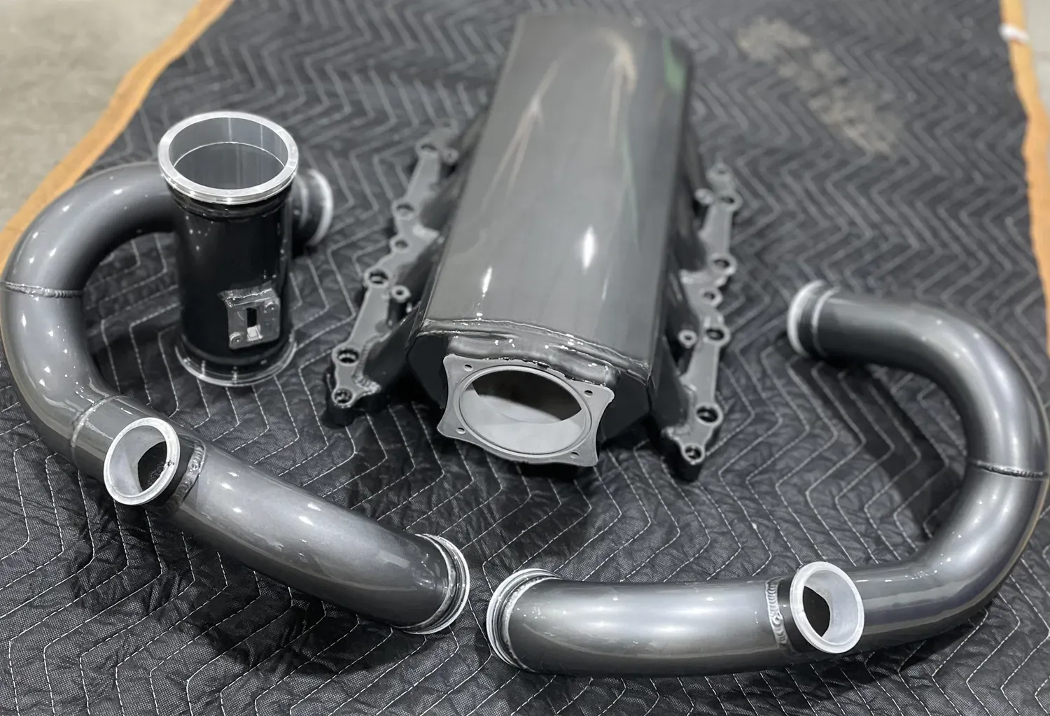 Gunmetal-coated intake and charge pipes lined up after curing