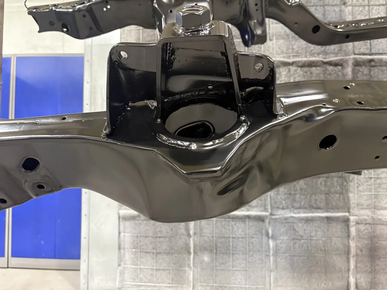 Large vehicle subframe coated in satin black on a shop rack