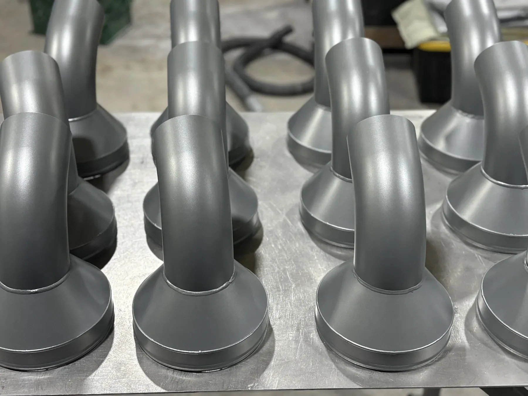 Batch of identical steel posts finished in grey and lined up on the bench after coating