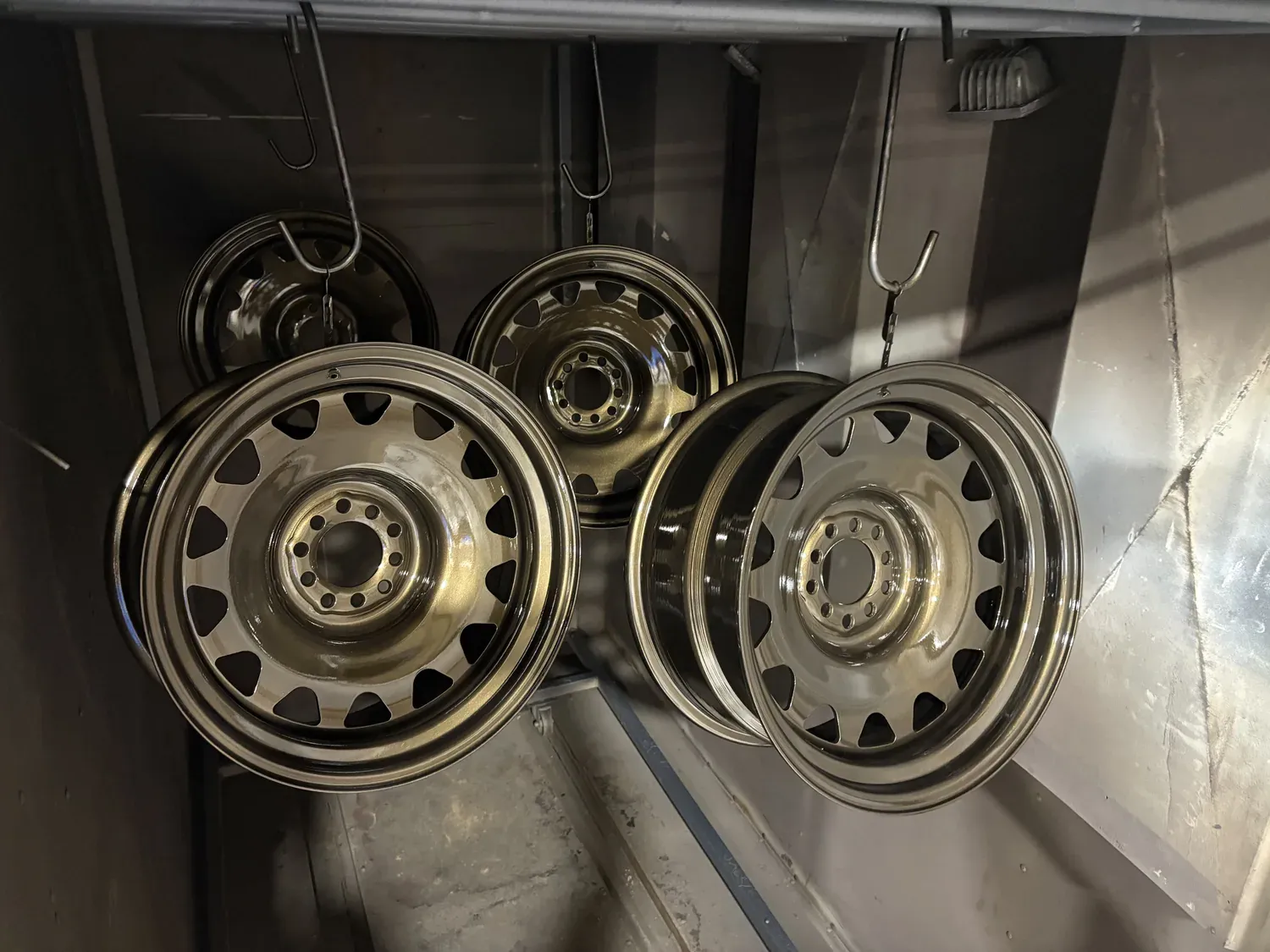 Steel wheels in bronze hanging in the coating booth after stripping