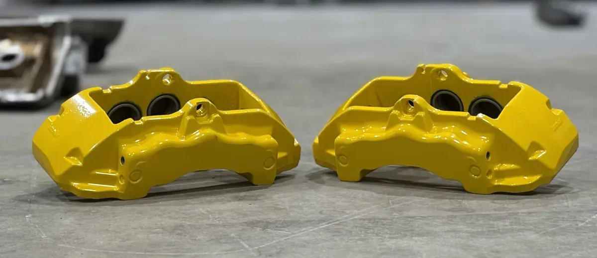 Pair of four-piston brake calipers powder coated in bright yellow